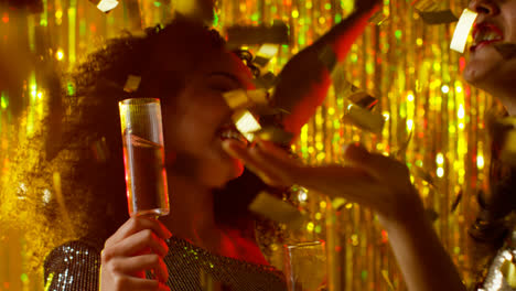 Close-Up-Of-Two-Women-Dancing-In-Nightclub-Bar-Or-Disco-Drinking-Alcohol-With-Falling-Gold-Confetti-3